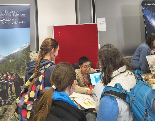 Dr Peidong Shi explains seismic aspects to school girls  while others look at the book: 'My mummy is a scientist'. Photo: Mr Kasongo Emmanuel Shutsha.